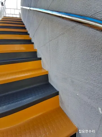 시공 전 건물 외부 계단, 노란색·회색 논슬립과 벽면 스테인리스 손잡이가 이어진 모습