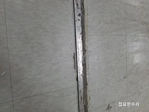 문턱 레일 옆 데코타일이 깨지고 벗겨져 있는 모습 (안산 출장 시공)
