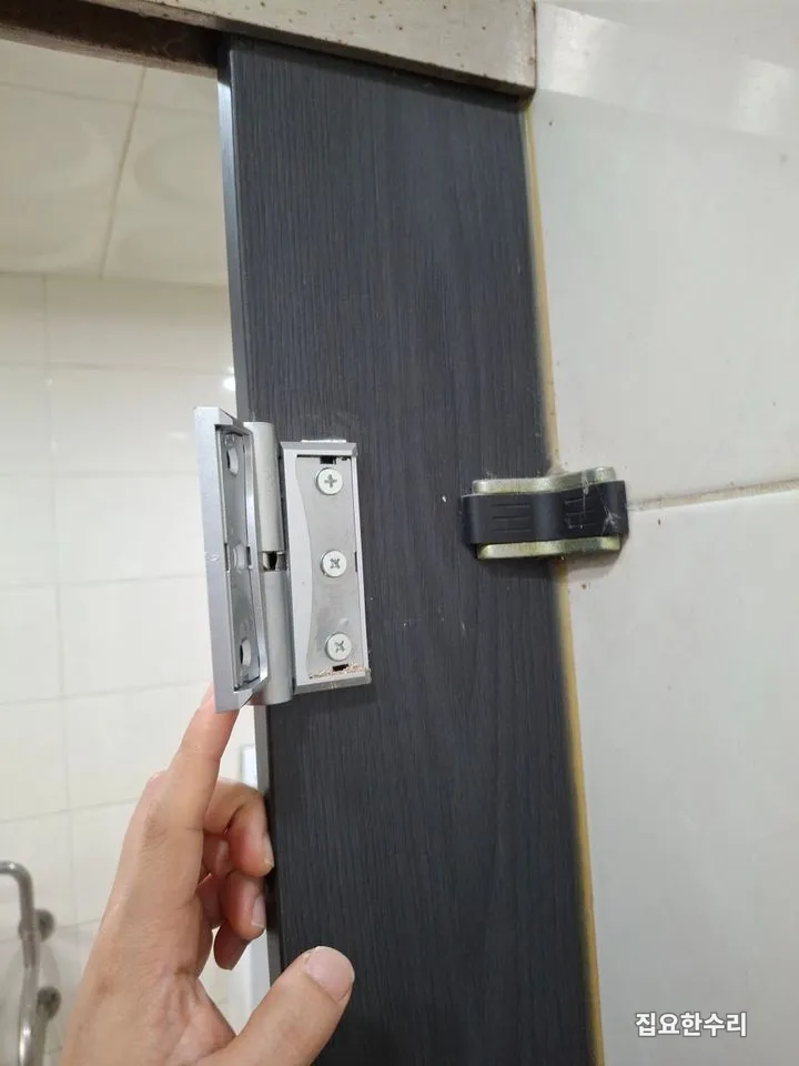 도어에 새 경첩을 대고 고정 위치를 맞추는 모습