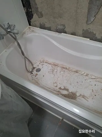철거 과정에서 나온 타일 조각과 분진이 쌓인 기존 욕조와 타일이 떨어진 뒷벽